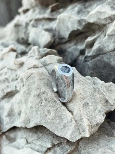 Silver signet ring with Picasso dolomite on natural rock background.
