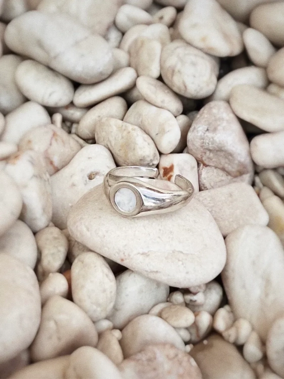 Silver signet ring with Polish opal displayed on natural stone background.