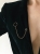 Modern gold brooch with delicate chain and deep green nephrite worn on blazer
